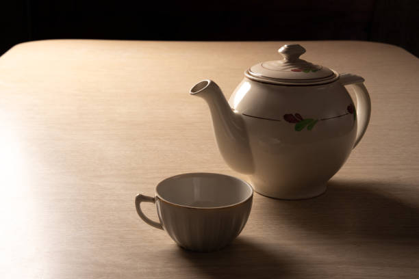 istock Teapot and cup of tea on a formica table, dark background, selective focus. 1329709079
