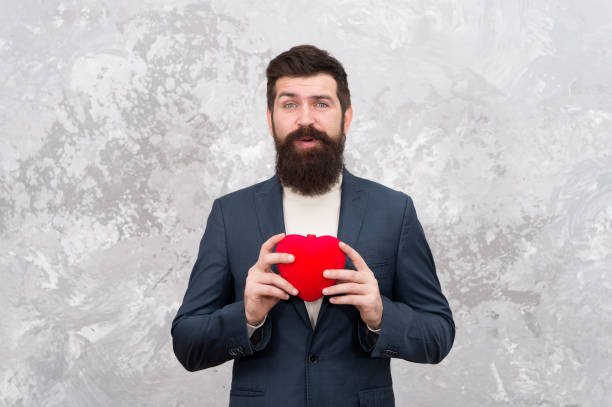istock Brought present. Bearded man hold red heart. Valentine present. Hipster give present abstract background. Present for Valentines day. Holiday giving. Donate for Valentines day 1329710394