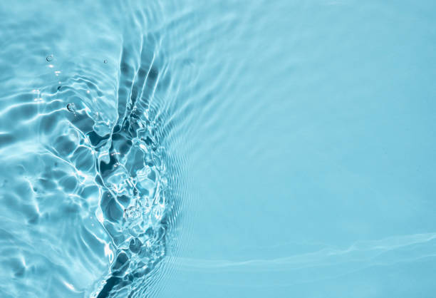 istock Trendy summer nature background. Blue liquid colored clear water surface texture with splashes bubbles. Water waves in sunlight Toner or Emulsion blue colored  background. 1329714345