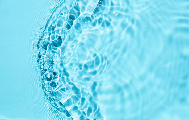 istock Trendy summer nature background. Blue liquid colored clear water surface texture with splashes bubbles. Water waves in sunlight Toner or Emulsion blue colored  background. 1329714395