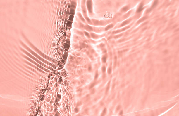 istock Blurred or defocused transparent clear water waves in sunlight. Pink liquid colored clear water surface texture with splashes bubbles. Trendy summer exotic banner. 1329714409