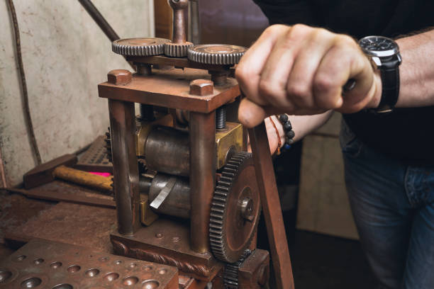 un bijoutier roule une feuille de métal pour l’utiliser dans son travail - rolling mill photos et images de collection