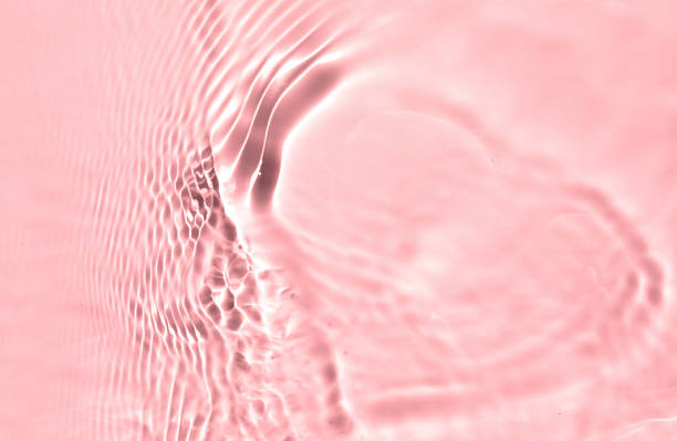 istock Blurred or defocused transparent clear water waves in sunlight. Pink liquid colored clear water surface texture with splashes bubbles. Trendy summer exotic banner. 1329714882
