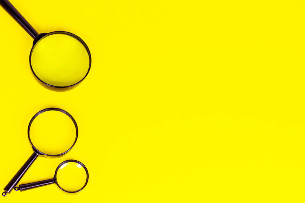 istock Black magnifying glass on light yellow background with copy space 1329716084