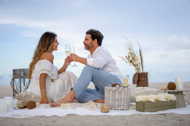 coppia amorevole in un appuntamento romantico in spiaggia facendo un brindisi - romance honeymoon couple vacations foto e immagini stock