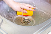 Cleaning metal sink with chemicals and sponge. Housework, housekeeping service, household duties concept