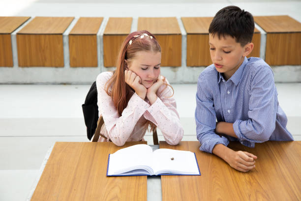 Pink hair teenager girl reading book, schoolboy boy brought a beetle to her, teenagers relationship concept Pink hair teenager girl reading book, schoolboy boy brought beetle to her, teenagers relationship concept define the relationship stock pictures, royalty-free photos & images