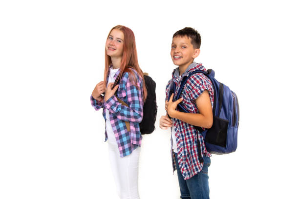 niño y niña adolescente de 11 años colegiala y colegiala mirando la cámara sobre fondo blanco con mochila y sonriendo. vestido con camisa a cuadros, camisa blanca - 10 11 years little boys child happiness fotografías e imágenes de stock