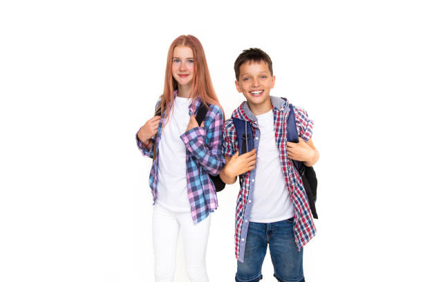 garçon et fille adolescent de 11 ans écolier et écolière regardant la caméra sur fond blanc avec sac à dos et souriant. vêtu d’une chemise à carreaux et d’une chemise blanche - 10 11 years little boys child happiness photos et images de collection