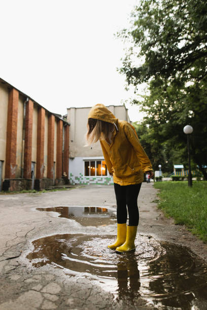 istock A woman in waterproof clothes having fun on the puddle 1329717519