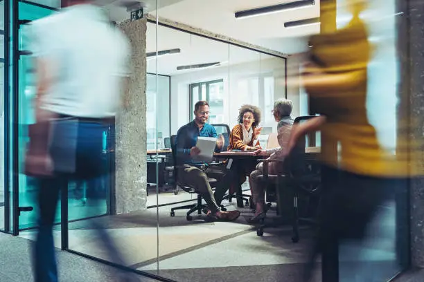 Group of business persons having a meeting in a closed glass conference room