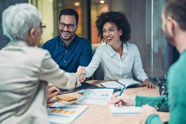 smiling businesswomen handshake over the table - partnership imagens e fotografias de stock