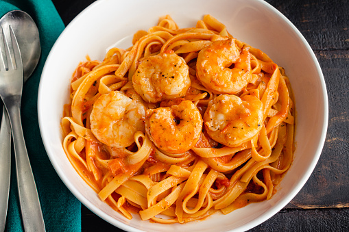 Bowls of shrimp and fettuccine pasta noodles in a creamy tomato sauce