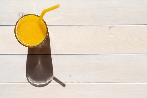 Fresh orange juice in glass on wooden background