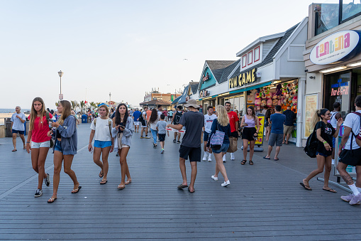 Point Pleasant, NJ, USA - July 16, 2021: Afternoon people walking on Jenkinson's Boardwalk outside food and arcade stores in Point Pleasant, NJ 2021