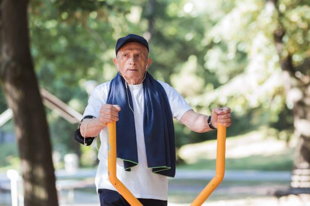 istock Senior man exercising on exercise equipment at park 1329729353