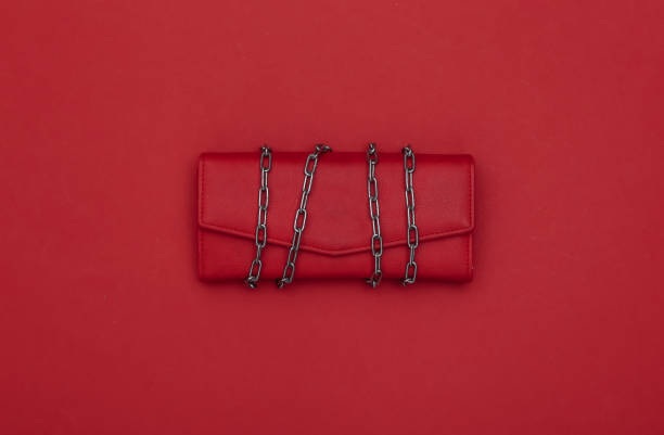 istock Leather wallet wrapped in a steel chain on red background. 1329730962