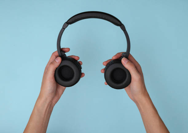 istock Hands holding stereo headphones on blue background 1329732109
