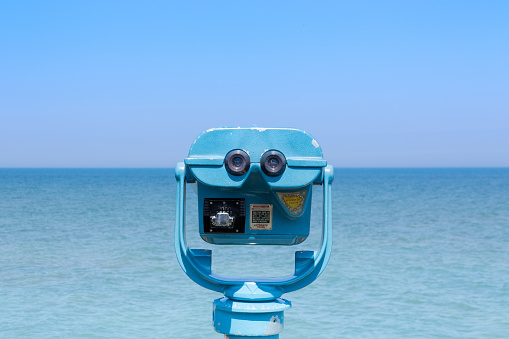 A sunny day and open water extend to the horizon in front of a beachfront tower viewer.