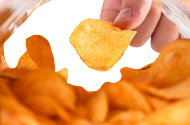 istock Mans hand takes chips from a pack, isolated. View from a packet of chips 1329740292