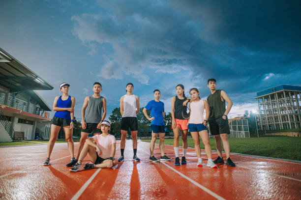 asiatische chinesische sportmannschaft athlet coole einstellung blickt am späten abend auf das leichtathletikstadion - mixed age stock-fotos und bilder