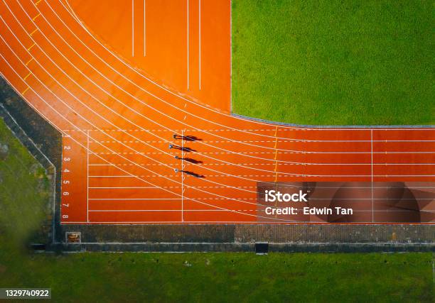Directly Above Drone Point Of View Asian Chinese Male Athlete Running At Mens Track Rainy Late Evening In Stadium Stock Photo - Download Image Now