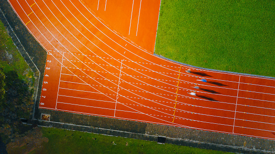 directly above drone point of view asian chinese male athlete running at men's track rainy late evening in stadium