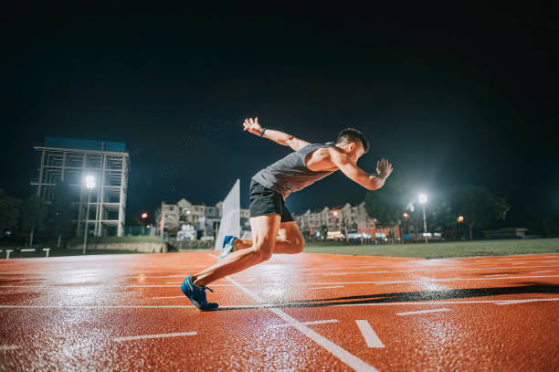 aerodynamic asian chinese male athletes sprint running at track and run towards finishing line at track and field stadium track rainy night - sports track track and field stadium sport night imagens e fotografias de stock