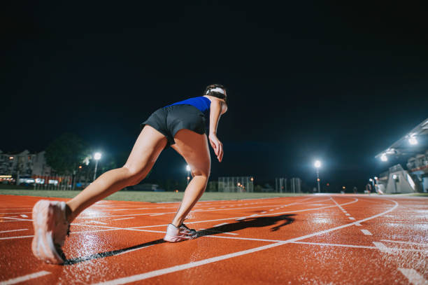 rear view aerodynamic asian chinese female athletes sprint running at track and run towards finishing line at track and field stadium track rainy night - sports track track and field stadium sport night imagens e fotografias de stock