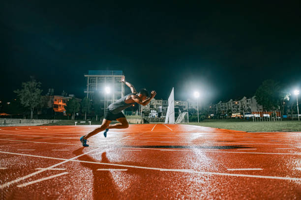 aerodinámicos atletas masculinos chinos chinos sprint corriendo en pista y correr hacia la línea de meta en la pista del estadio de atletismo pista noche lluviosa - sports track track and field stadium sport night fotografías e imágenes de stock