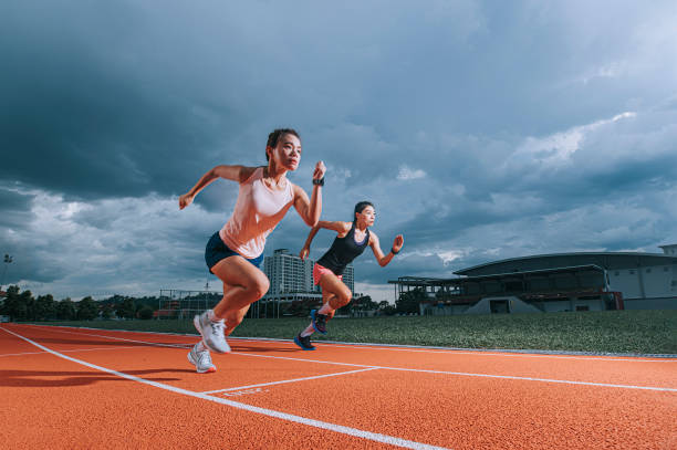 asian chinese female athletes running at track cloudy late evening in track and field stadium asian chinese female athletes running at track cloudy late evening in track and field stadium scoring run stock pictures, royalty-free photos & images