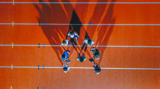 directly below drone point of view asian chinese athletes and captain lining up at track and field stadium at night - sports track track and field stadium sport night imagens e fotografias de stock