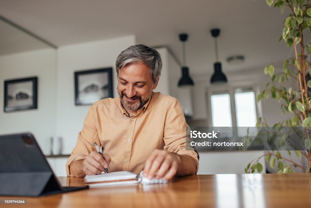 Adult man, working on his thesis, at home. Adult man, fixing the grammar mistakes in his science paper. Mature Men Stock Photo