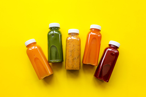 Fresh juices or cocktails of fruits and vegetables in bottles on a yellow background. The concept of a healthy diet or diet. Fresh organic ingredients