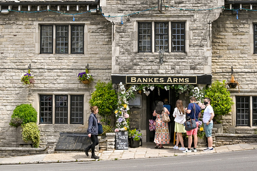 Corfe Castle, Dorset, England - June 2021: People queuing at the entrance to the Bankes Arms pub in the village.