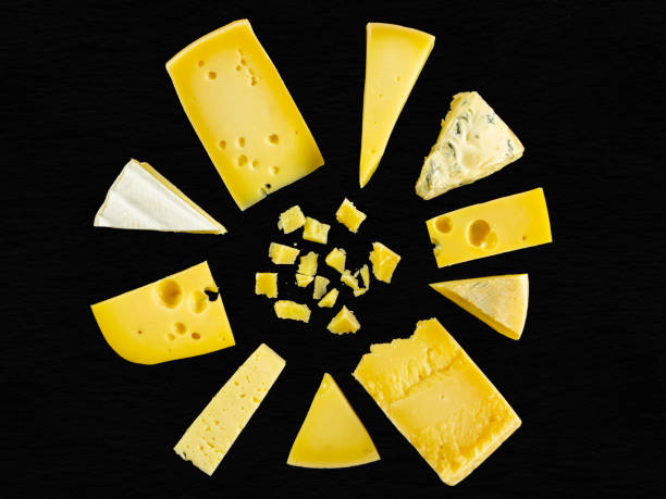 Cheeses on a black background. Different types of hard and soft cheeses: parmesan, emmental, brie, parmesan, cheese with mold, gorgonzola. Flat lay. stock photo