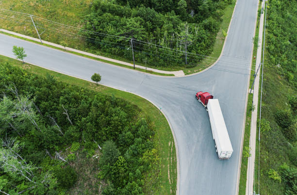 Semi Truck Turning at Intersection A wide angle drone view of a semi truck making a left turn in an industrial district. turning stock pictures, royalty-free photos & images