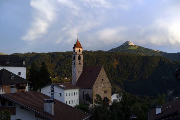 The clock painted outside the bell tower of the church in Selva di Val Gardena into the Dolomites area