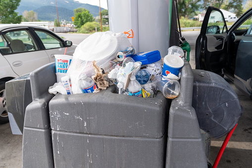Cody, Wyoming - July 4, 2021: Overflowing garbage bins stuffed with trash from cars at a gas station