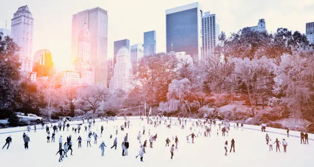 Ice skaters having fun in New York Central Park in fall with sunrise effect