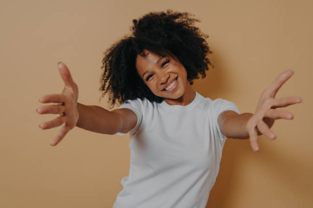 feliz mujer afroamericana amable vestida con camisa blanca ofreciendo abrazos, dando la bienvenida al cliente - warm welcome fotografías e imágenes de stock