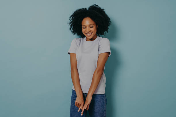 istock Young african lady looking down with with shy timid face expression, isolated over blue background 1329754566
