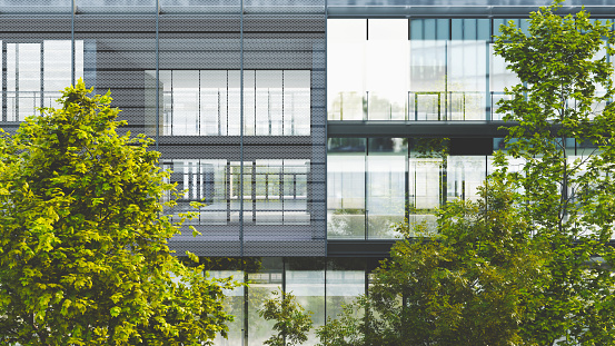 High section of a modern building surrounded by trees.