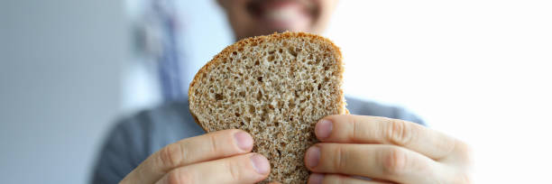 閉じる幸せな男はピース全粒粉パンを保持しています - bakery bread breakfast close up ストックフォトと画像