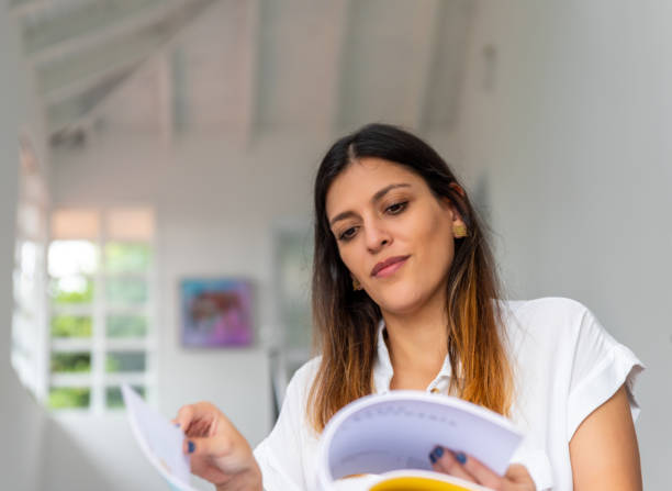 istock Smiling latina woman reading a book at home 1329760042