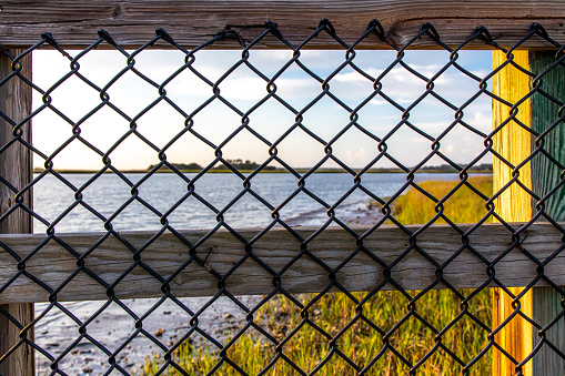 A chain link fence lines the marshy edge of a tidal creek on Big Talbot Island near Jacksonville, Florida.