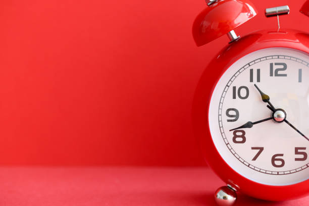 istock Red alarm clock on red background closeup 1329761111