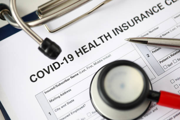 istock Silver pen lying at covid-19 insurance claim blank 1329761157