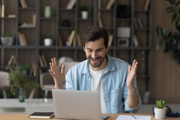istock Emotional happy young man celebrating getting good news notification. 1329762911