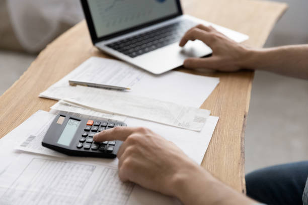 istock Close up young man using calculator summarizing domestic utility bills. 1329762930